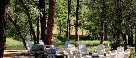 Un espacio al aire libre con sillas Adirondack y una parrilla.