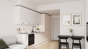 A modern kitchen with white cabinets, a black countertop, and a dining area with two black chairs. - Toivo Studios (Espoo)
