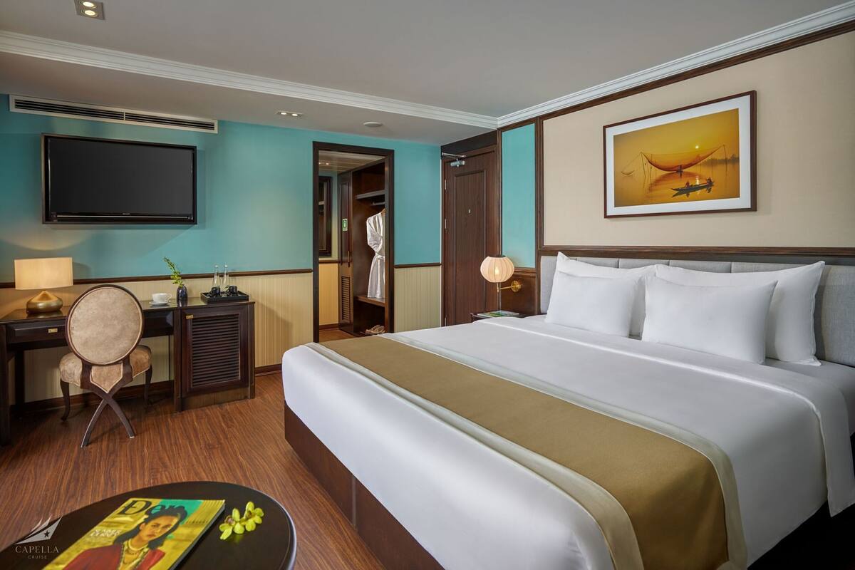 Een hotelkamer met een bed, een bureau, een televisie en een schilderij aan de muur.