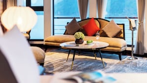 A modern hotel room with a sofa, a round coffee table, and a view of the sea. - Halong CAPELLACRUISE - Member of Lyra Cruise Collection (Tuan Chau)