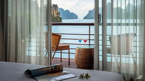 A balcony with wicker chairs, a table with a magazine, and two drinks on a small table. - Halong CAPELLACRUISE - Member of Lyra Cruise Collection (Tuan Chau)