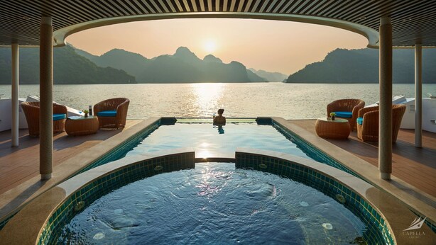 A pool area with a view of the sea and mountains, surrounded by wicker furniture and a covered roof. - Halong CAPELLACRUISE - Member of Lyra Cruise Collection (Tuan Chau)