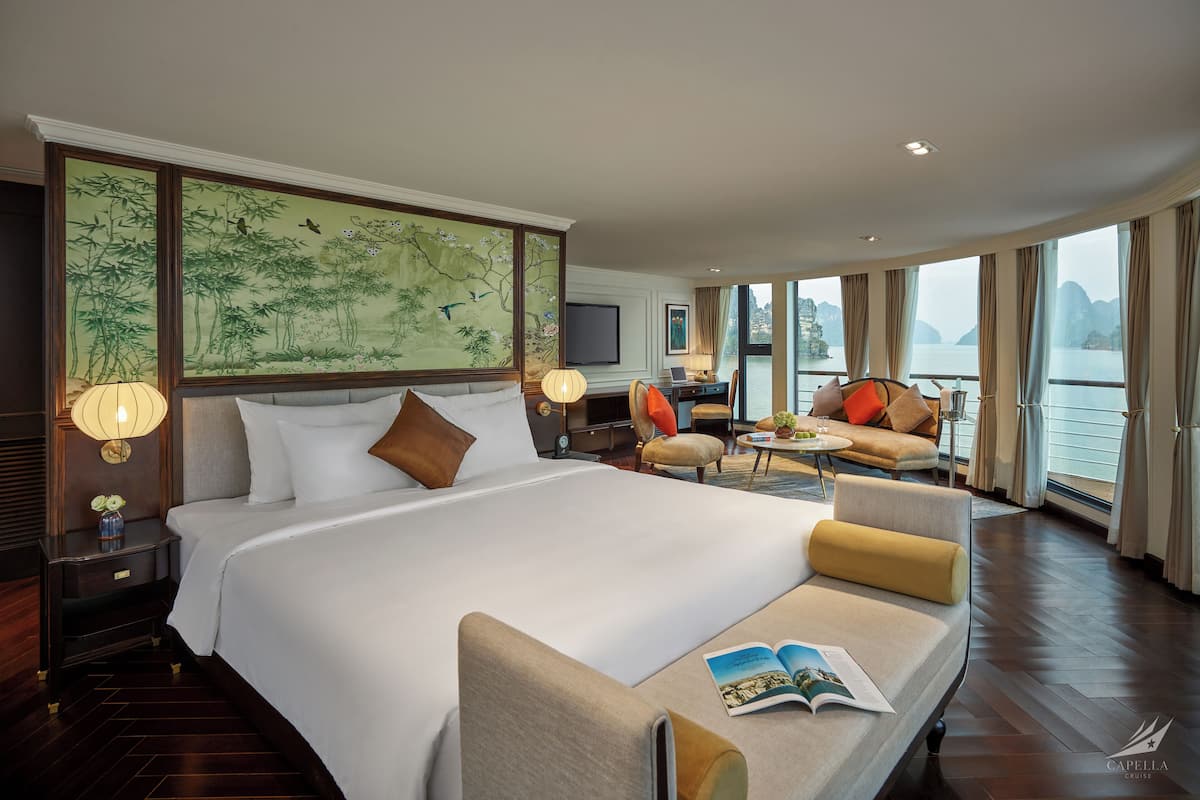 Een hotelkamer met een groot bed, een bank, een bureau en uitzicht op het water.