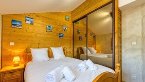 Un dormitorio con paneles de madera, un espejo grande, dos camas y obras de arte en las paredes.