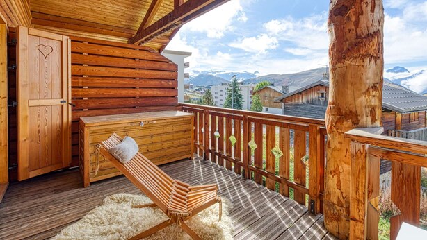 Una terraza de madera con un banco y una hamaca, con vistas a un paisaje montañoso.
