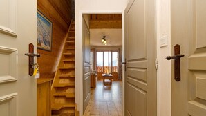 Una escalera de madera que conduce a un balcón con vistas, piso de madera y una puerta con la llave en la cerradura.
