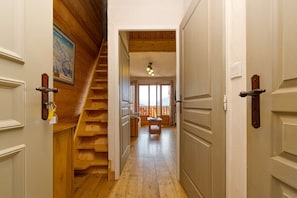 Un escalier en bois menant à un balcon offrant une vue dégagée, un plancher en bois et une porte avec une clé dans la serrure.