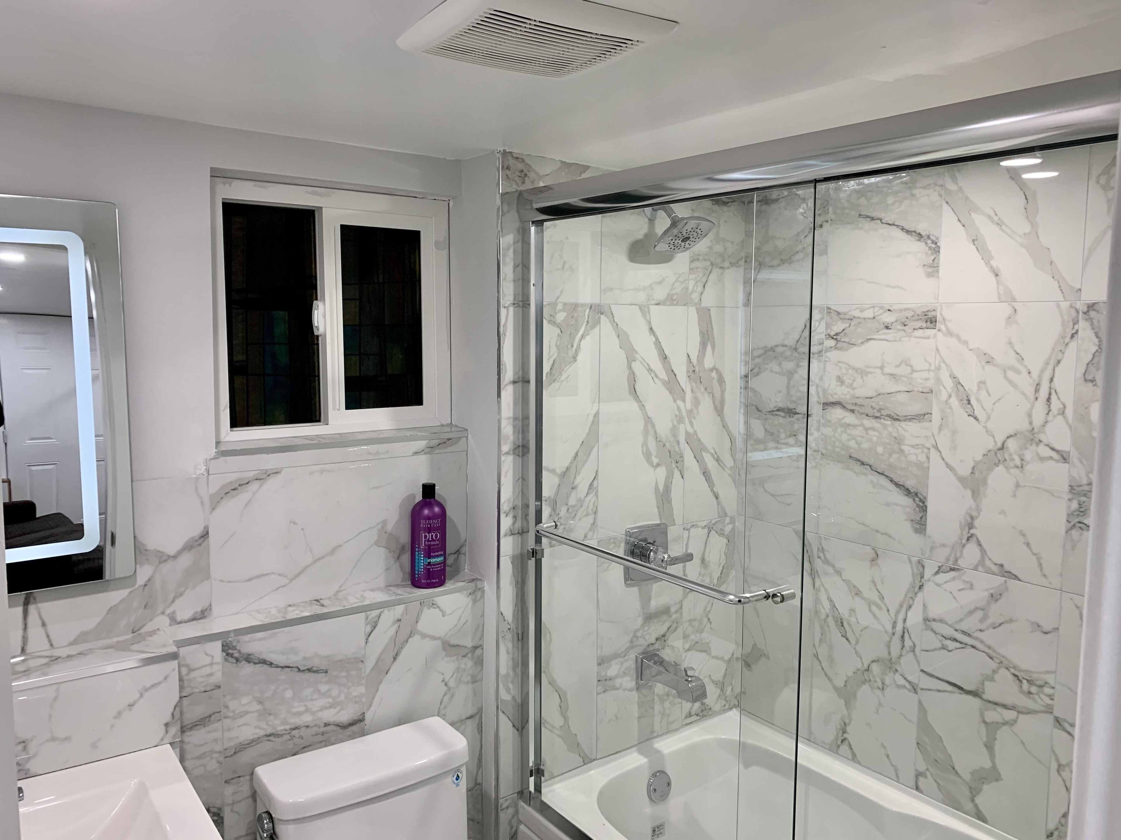 A modern bathroom with a glass-enclosed shower, a toilet, and a sink.