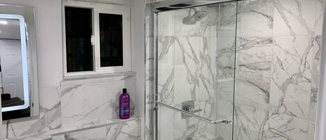 A modern bathroom with a glass-enclosed shower, a toilet, and a sink.