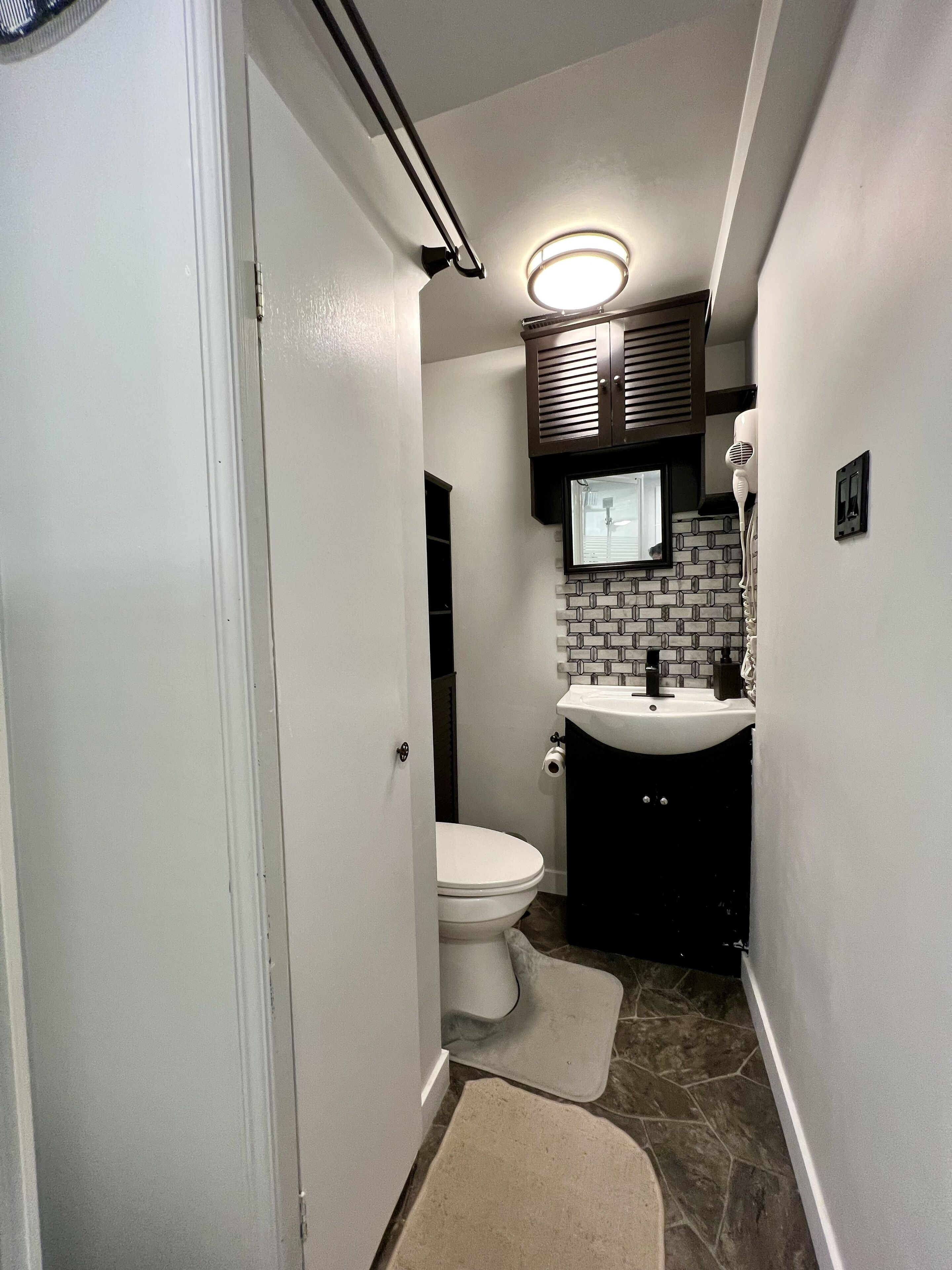 A compact bathroom with a toilet, sink, and a towel rack.