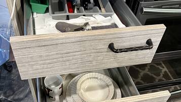 A kitchen counter with a paper towel holder, a coffee maker, and a drawer with kitchen utensils.