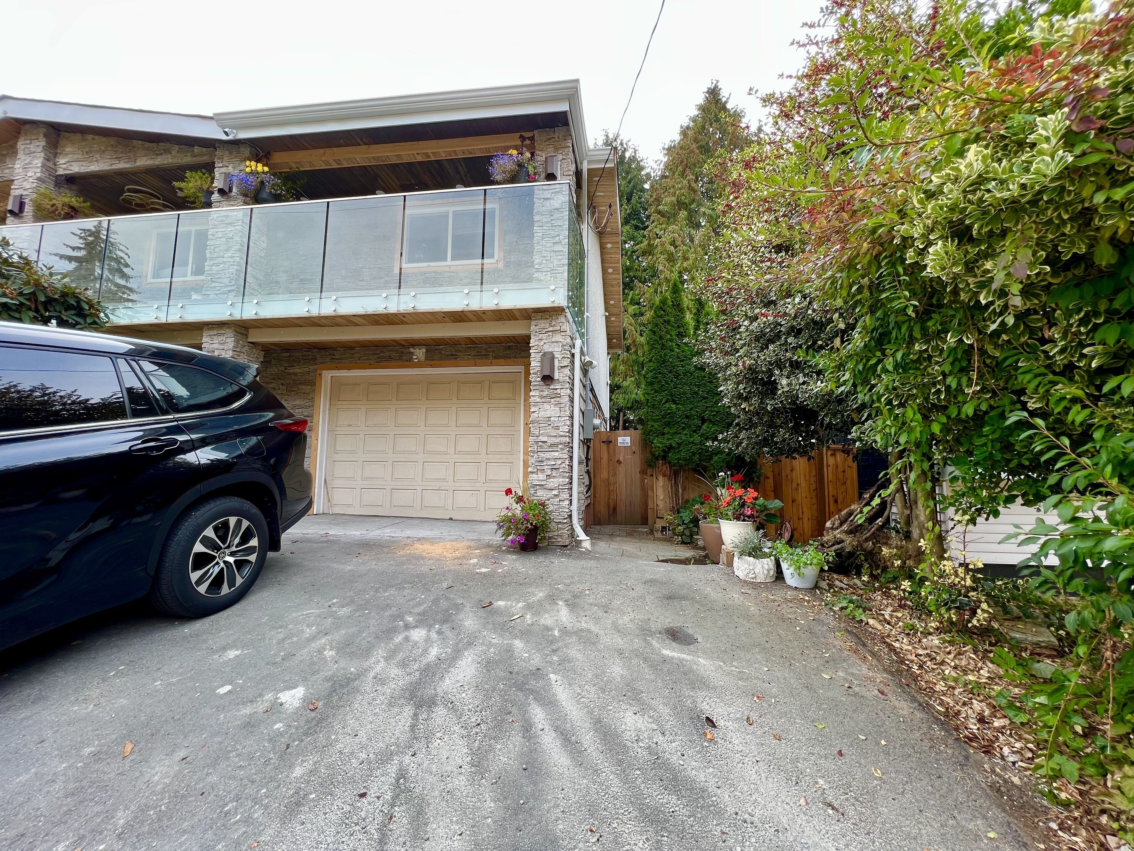 Ein zweistöckiges Haus mit Garage, Balkon und Auffahrt.