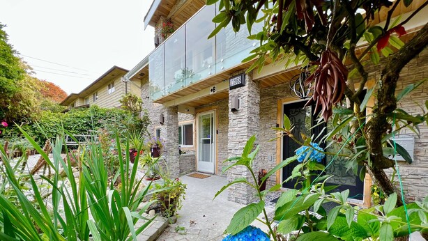 A stone building with a glass balcony, a stone entrance, and a paved pathway. - Fully AirConditioned Resort Style home living w/Hottub,outdoor shower and  pool. (Delta)