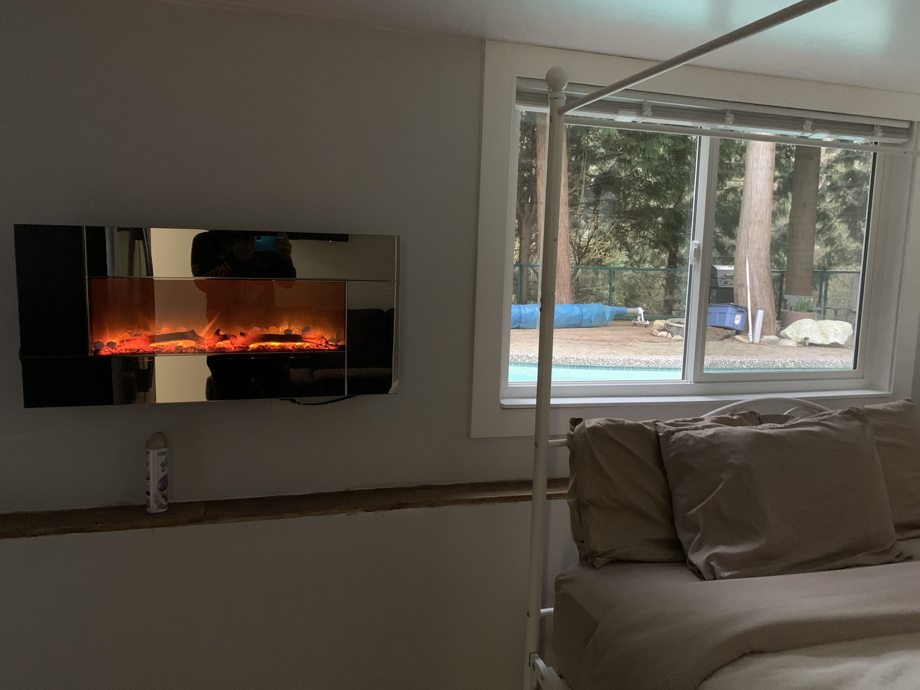 A room with a bed, a TV mounted on the wall, and a window with a view of an outdoor area.