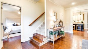 Eine Treppe führt zu einem Schlafzimmer, ein Konsolentisch mit Pflanzen und ein Küchenbereich sind zu sehen.