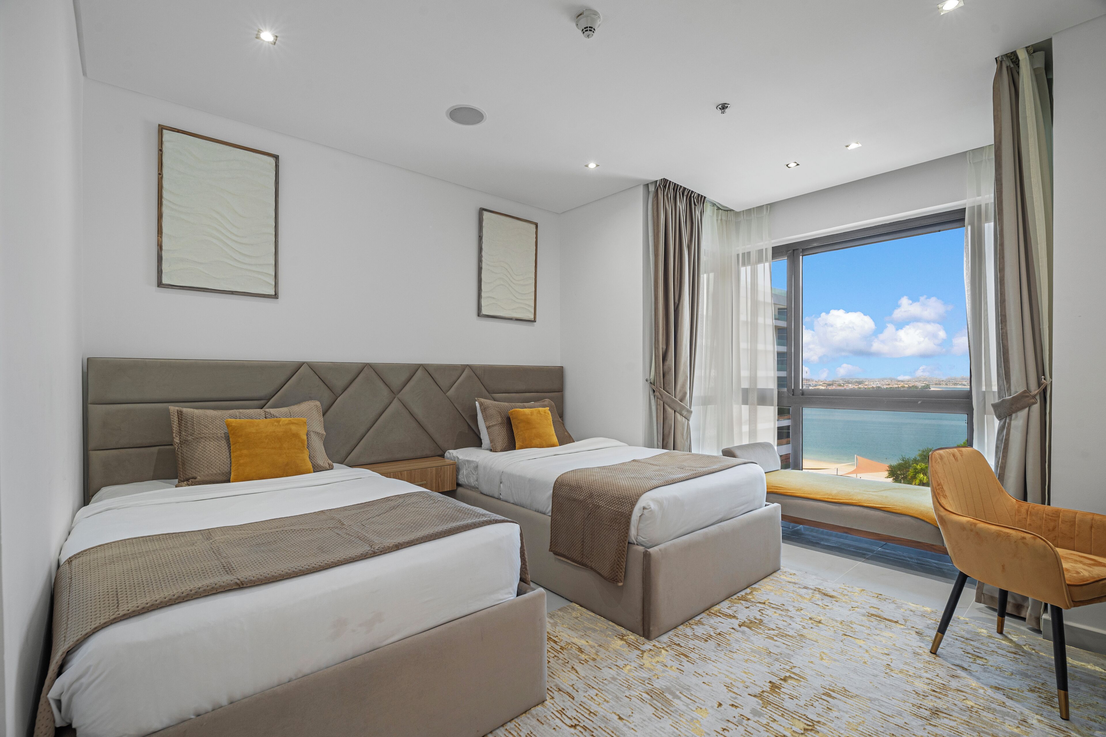 A hotel room with two beds, a large window with a view, and a chair.