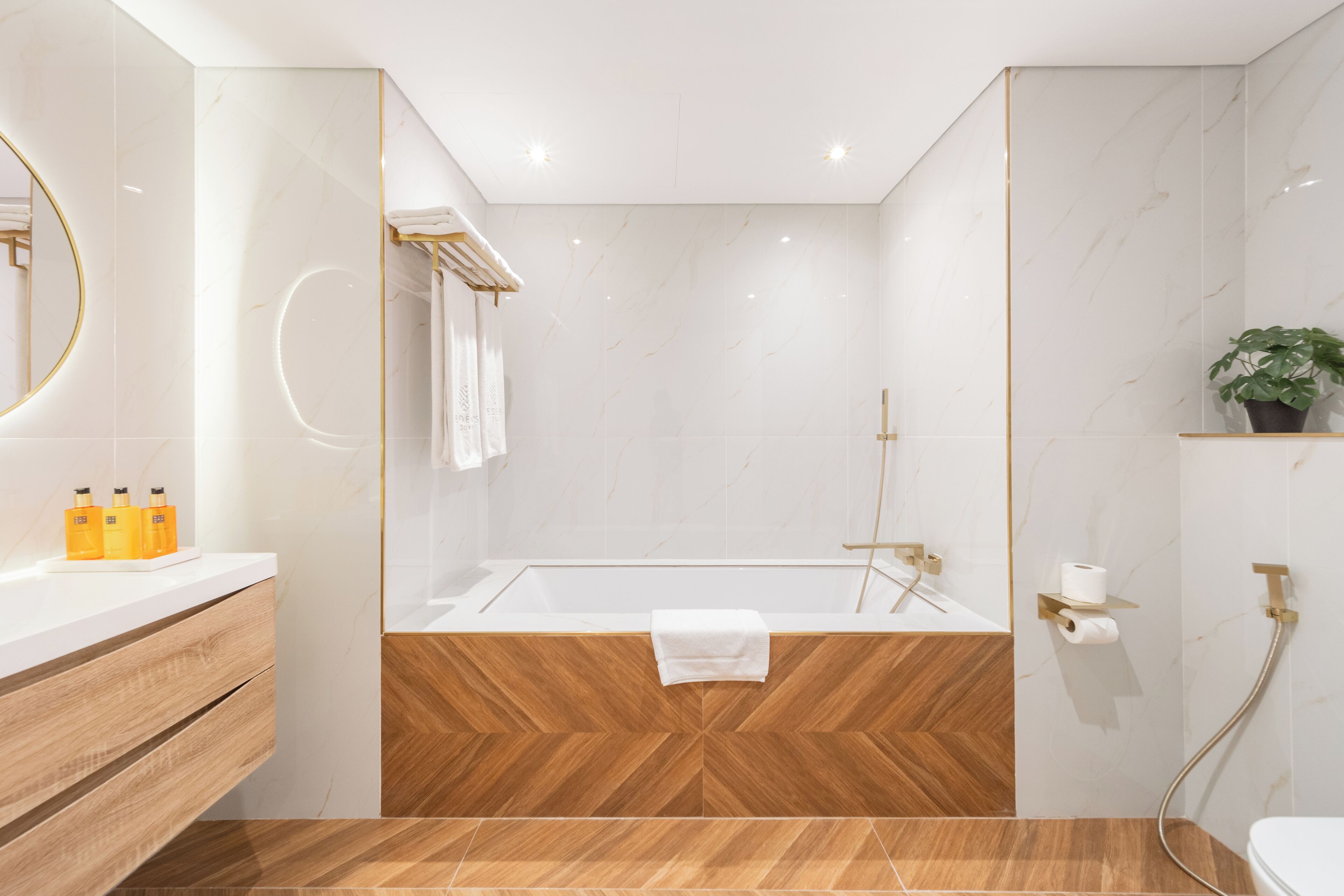 Une salle de bain moderne avec un meuble-lavabo en bois, un grand miroir, une baignoire et un espace douche.