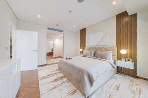 A modern bedroom with a large bed, bedside tables, a wall-mounted TV, and a wooden accent wall.