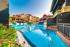 A swimming pool with a tiled deck, surrounded by hotel buildings with traditional architectural style.