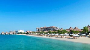 Een strandhotel met meerdere gebouwen, een zandstrand en parasols.