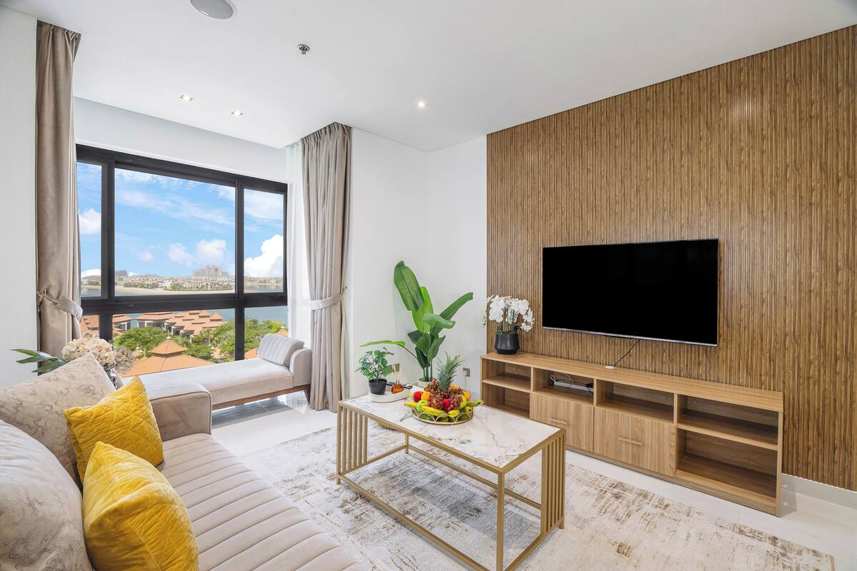 Een moderne woonkamer met een grote televisie, een bank, een salontafel en uitzicht op de stad.