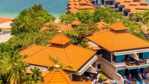 Een resort met meerdere gebouwen, voorzien van oranje pannendaken, een strand en een helder uitzicht op de zee.