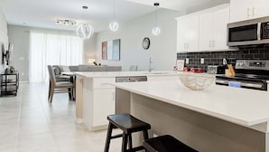 Een moderne keuken met witte kasten, een groot eiland en een zwarte magnetron.