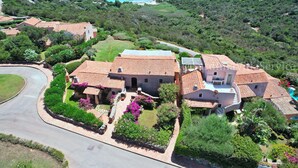 A large villa with a terracotta roof, surrounded by lush gardens and a view of the sea. - Apartment Dream - Cala Granu (Arzachena)