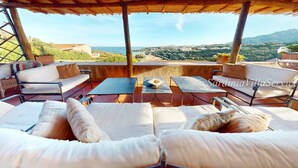 A terrace with outdoor seating, a table, and a view of the landscape. - Apartment Dream - Cala Granu (Arzachena)