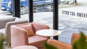 A seating area with a pink sofa and a small round table, a window with a view of a street and parked cars, and a sign reading "BROWN DOT HOTEL". - Browndot Hotel Namchuncheon (Chuncheon)