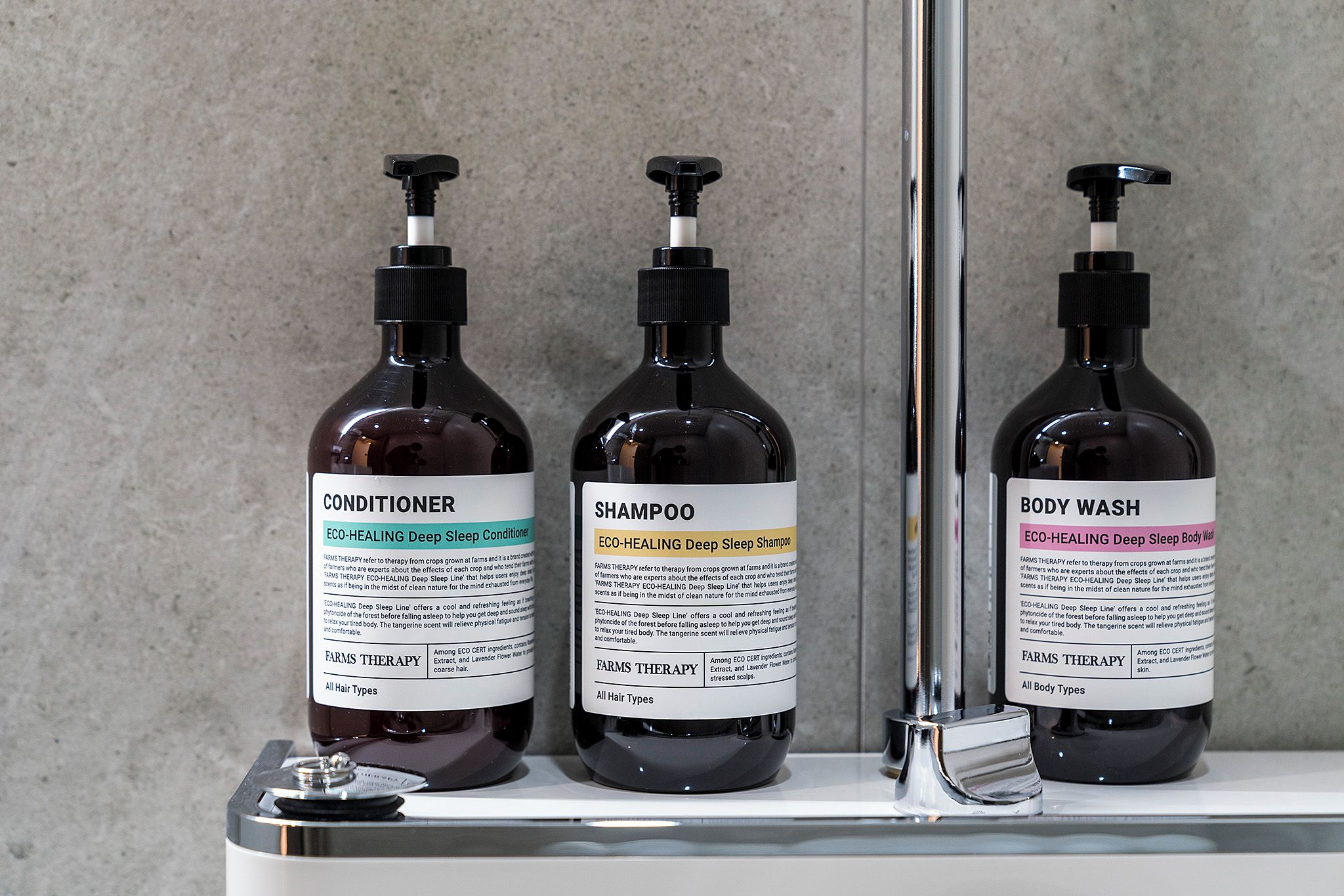 Tres botellas de productos Farms Therapy en una estantería.