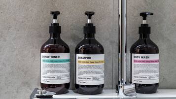 Tres botellas de productos Farms Therapy en una estantería.