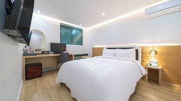 Ein modernes Hotelzimmer mit Bett, Schreibtisch, Fernseher und einem Fenster mit Jalousien.