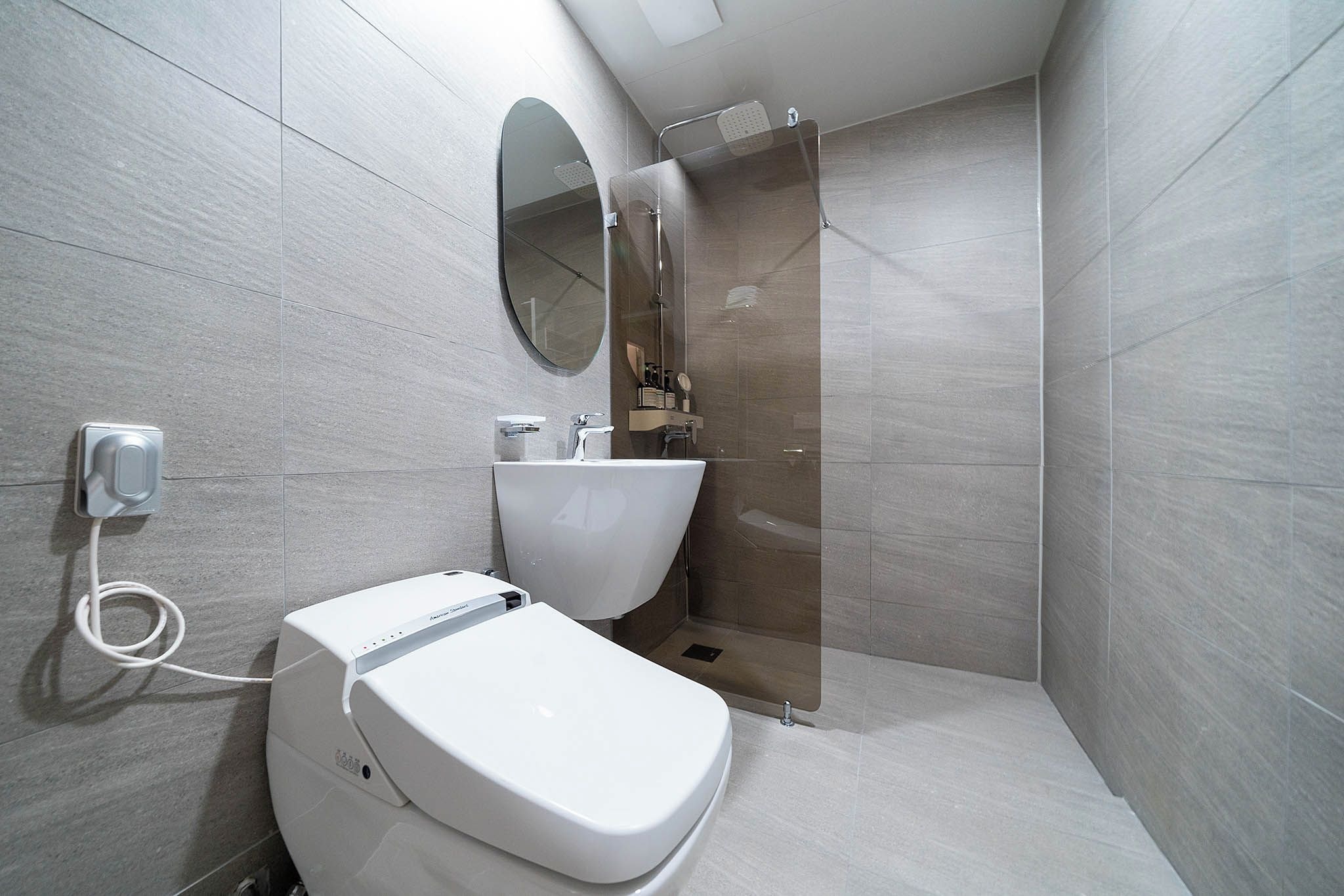 A modern bathroom with a toilet, sink, and shower.