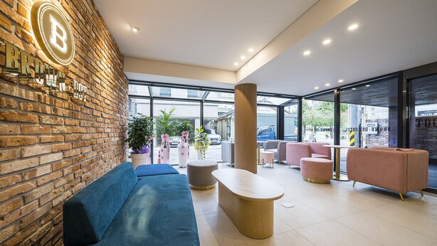 A modern lobby with a brick wall, blue seating, and a large window offering a view of the outside. - Browndot Hotel Namchuncheon (Chuncheon)