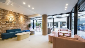 A modern interior with a brick wall, a blue sofa, a wooden coffee table, and a pink seating area. - Browndot Hotel Namchuncheon (Chuncheon)