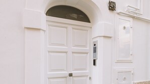 A white building with a large arched entrance, a sign reading "SUITE 1212", and a small number "45" plaque. - Suite1212 Bandiera  (Monopoli)
