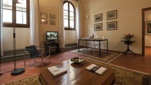 A room with a wooden coffee table, a television, a dining table with chairs, and a small side table with a vase. - San Miniato Apt - Luxury Apartments at 20 steps from Duomo; Elevator equipped. (Firenze)
