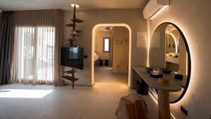A modern hotel room with a large TV, a mirror, and a desk with a bowl and tissues. - Brilliance of Mykonos (Mykonos)