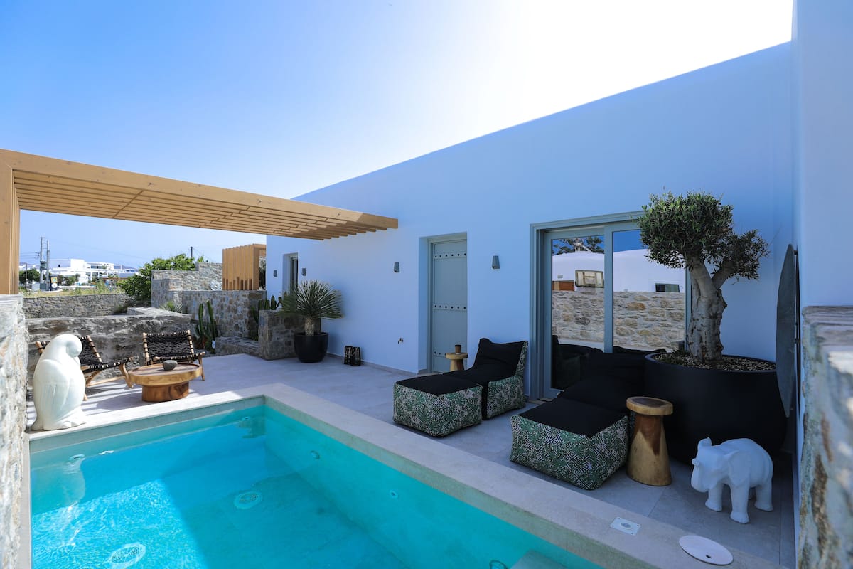 A modern outdoor pool area with a pergola, lounge chairs, and a small table.