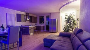 Een moderne woonkamer met een bank en een eethoek met stoelen en een tafel.