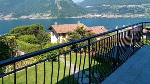 Een balkon met uitzicht op een meer, bergen en een stad op de achtergrond.