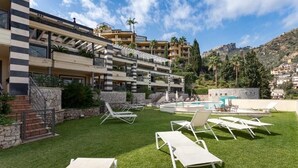Un hotel con zona de piscina, mobiliario exterior y vistas del paisaje circundante.