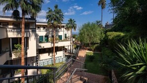 Un edificio de varios pisos con balcones, rodeado de exuberante vegetación y palmeras.