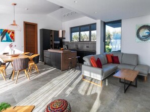 A modern living space with a dining area, kitchen, and seating area. - Martincic Residence (Marcana)