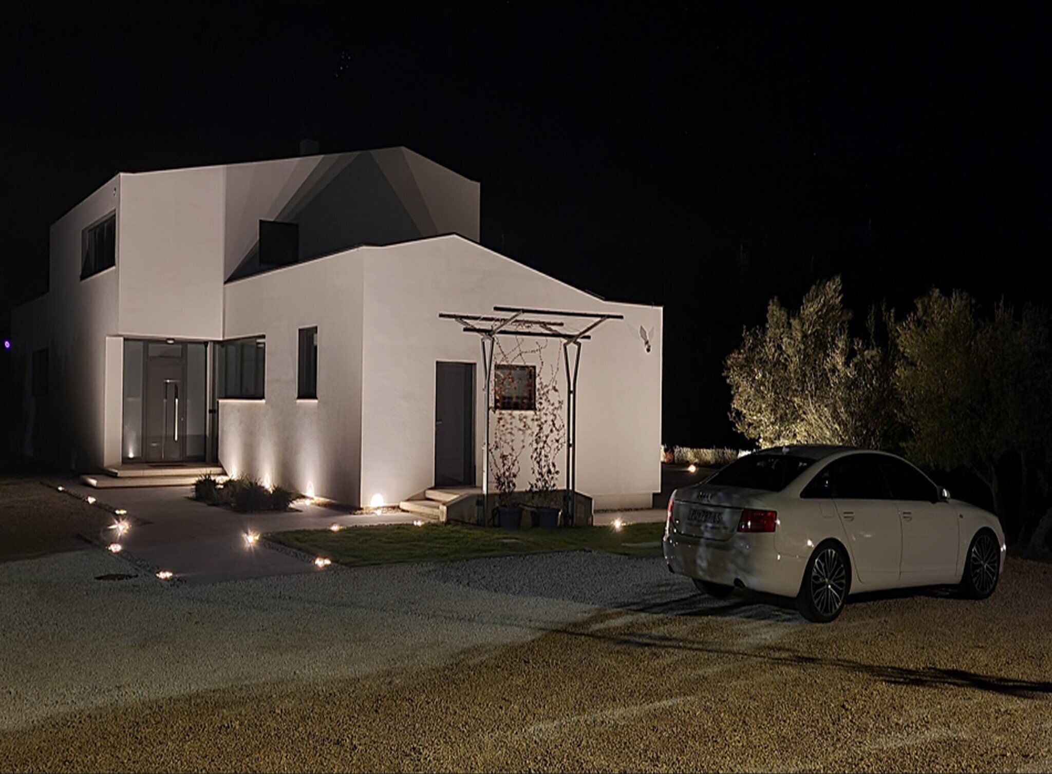 A modern two-story house with a car parked in the driveway.