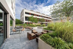 A modern outdoor patio area with seating arrangements and planters. - PLAZA INN Ulm (Ulm)