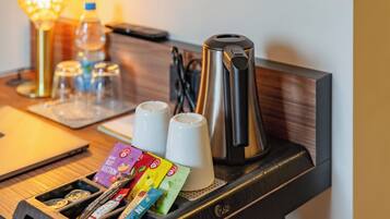 Une chambre d’hôtel équipée d’une machine à café, de deux tasses, d’un plateau avec des en-cas, d’un ordinateur portable et d’une bouteille d’eau.