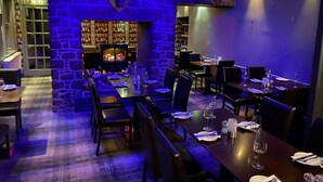 A restaurant with stone walls, a fireplace, and tables set for dining. - The Castle Inn (North Berwick)