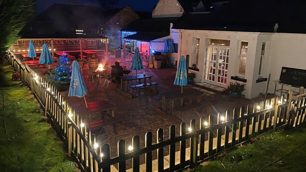 A patio area with outdoor seating, a Christmas tree, and a sign indicating a smoking area. - The Castle Inn (North Berwick)